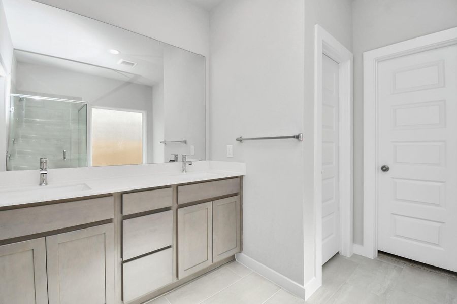 Escape to a spa-like oasis in this primary bathroom. Enjoy a walk-in shower with tile surround, a separate garden tub with custom detailing, and an elegant vanity featuring light countertops, modern hardware, and beautiful recessed lights. Experience luxury and relaxation in every detail. Sample photo of completed home with similar floor plan. Actual colors and selections may vary.
