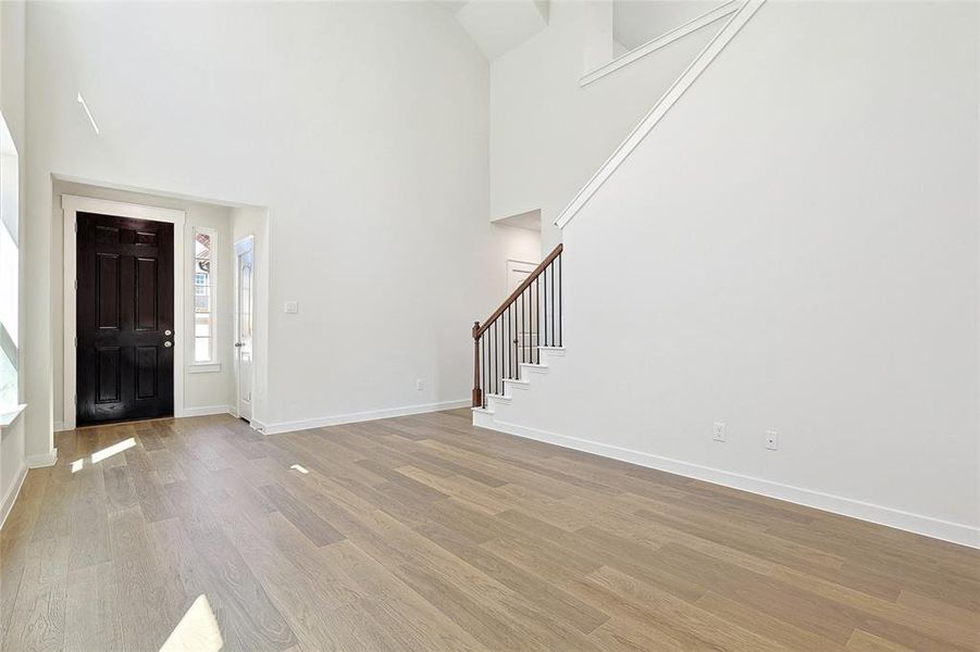 Foyer entrance featuring a towering ceiling and light hardwood / wood-style flooring