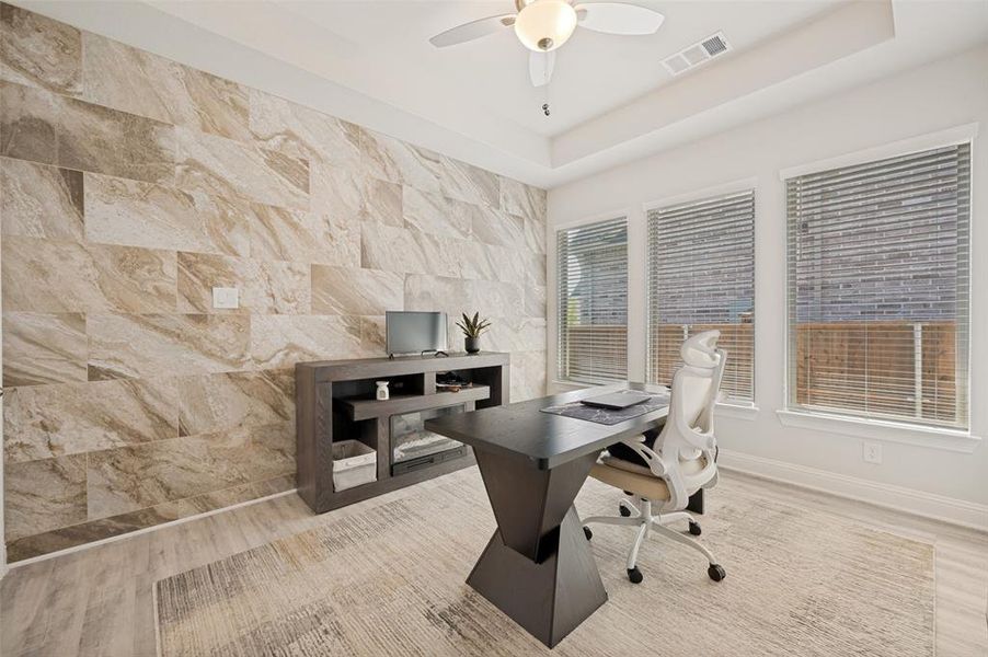 Beautiful home office featuring a dramatic custom stone accent wall, abundant natural light, and a sophisticated workspace perfect for working from home. The designer finishes create a productive and inspiring environment while adding a unique architectural focal point. Beautiful home office featuring a dramatic custom stone accent wall, abundant natural light, and a sophisticated workspace perfect for working from home. The designer finishes create a productive and inspiring environment while adding a unique architectural focal point.