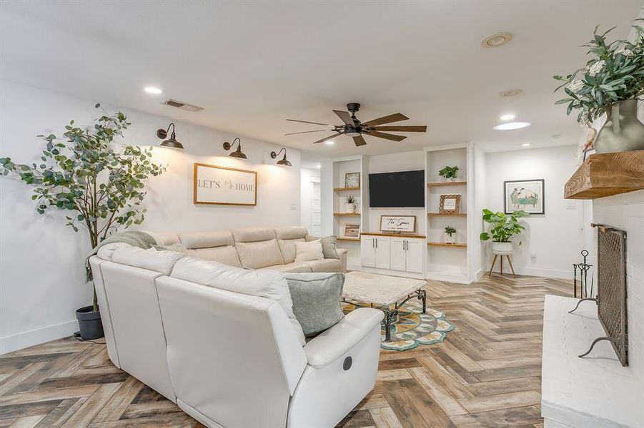 Living area with a fireplace, parquet flooring, ceiling fan, and recessed lighting