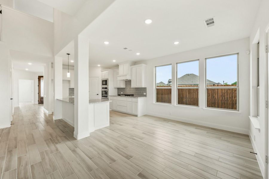 Open-concept living area and kitchen with white cabinets, light wood floors, and large windows Open-concept living area and kitchen with white cabinets, light wood floors, and large windows