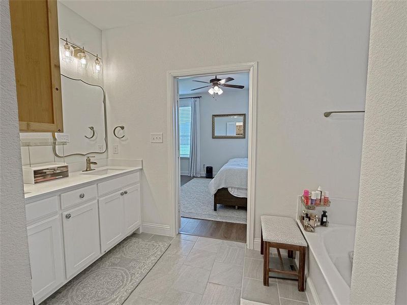 Bathroom with vanity, ensuite bath, ceiling fan, and light tile patterned floors Bathroom with vanity, ensuite bath, ceiling fan, and light tile patterned floors