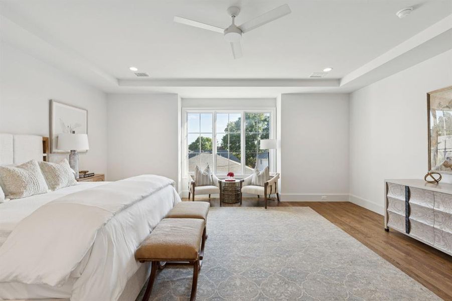 Bedroom featuring wood finished floors, ceiling fan, recessed lighting, and a raised ceiling Bedroom featuring wood finished floors, ceiling fan, recessed lighting, and a raised ceiling