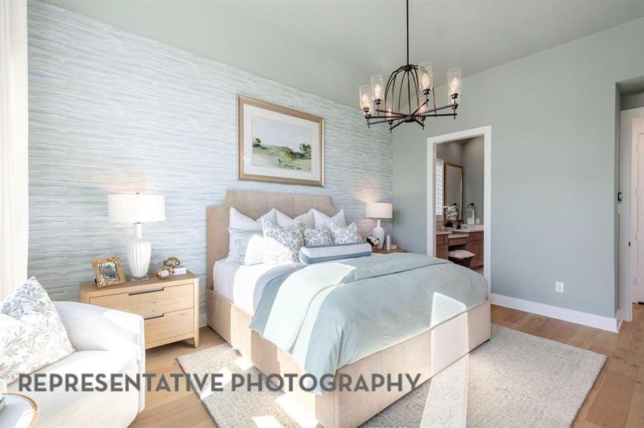 Bedroom featuring wood finished floors, a chandelier, and connected bathroom