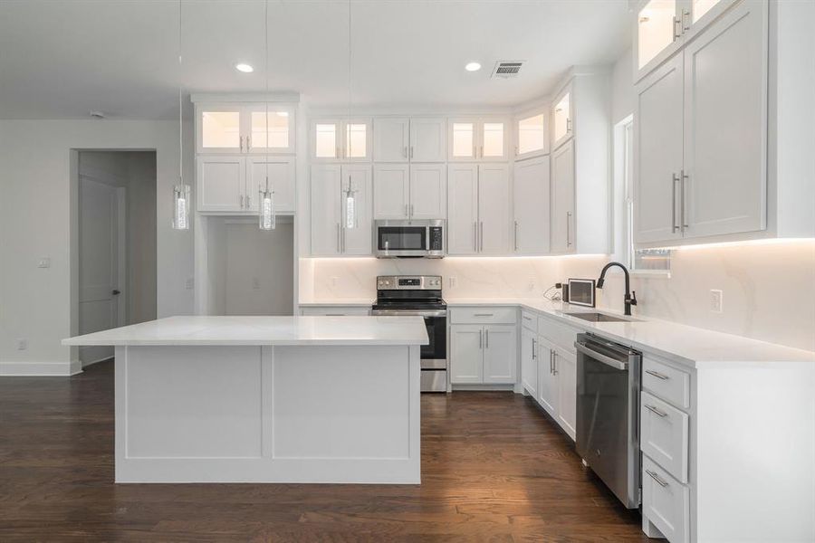 Kitchen with white cabinets, stainless steel appliances, dark hardwood / wood-style flooring, and a center island