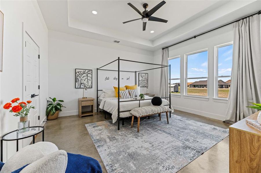Bedroom featuring finished concrete flooring, a raised ceiling, recessed lighting, and ceiling fan Bedroom featuring finished concrete flooring, a raised ceiling, recessed lighting, and ceiling fan