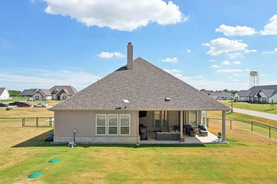 Back of property featuring covered patio and fenced backyard.