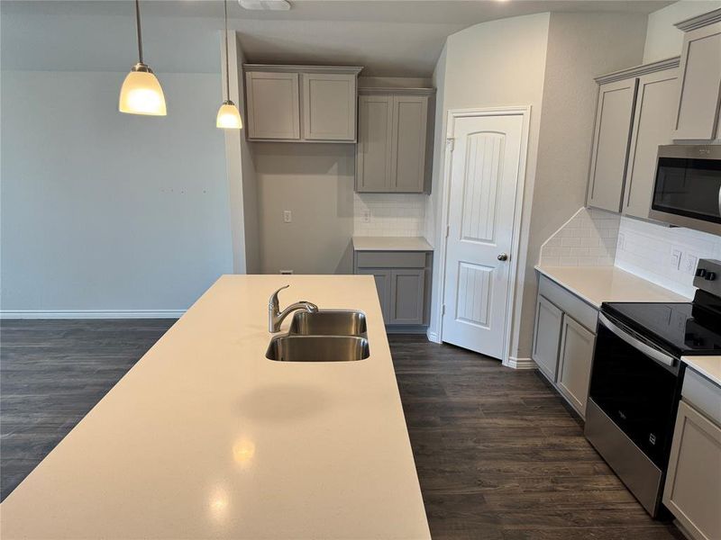 Kitchen featuring gray cabinets, stainless steel appliances, pendant lighting, dark wood-style floors, and backsplash