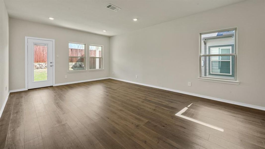 Spacious room featuring wood-finish flooring, recessed lighting, and light-toned walls