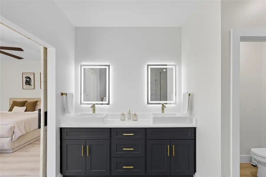 Bathroom featuring light wood-style floors, double vanity, and a shower