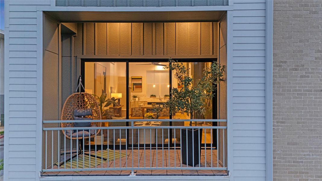 Private balcony featuring a brick-patterned floor, metal railings, and siding exterior