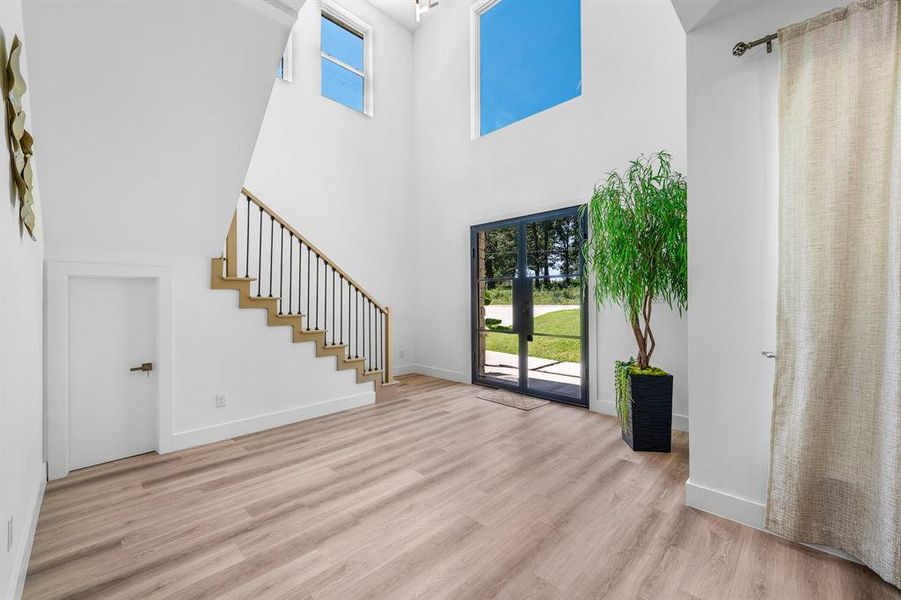 Entrance foyer with stairway, light wood finished floors, a high ceiling, and french doors Entrance foyer with stairway, light wood finished floors, a high ceiling, and french doors
