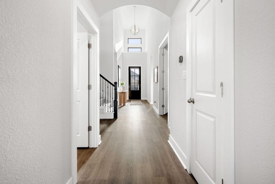 Step into a luminous entryway featuring an arched ceiling and rich wood flooring leading to a stylish staircase.