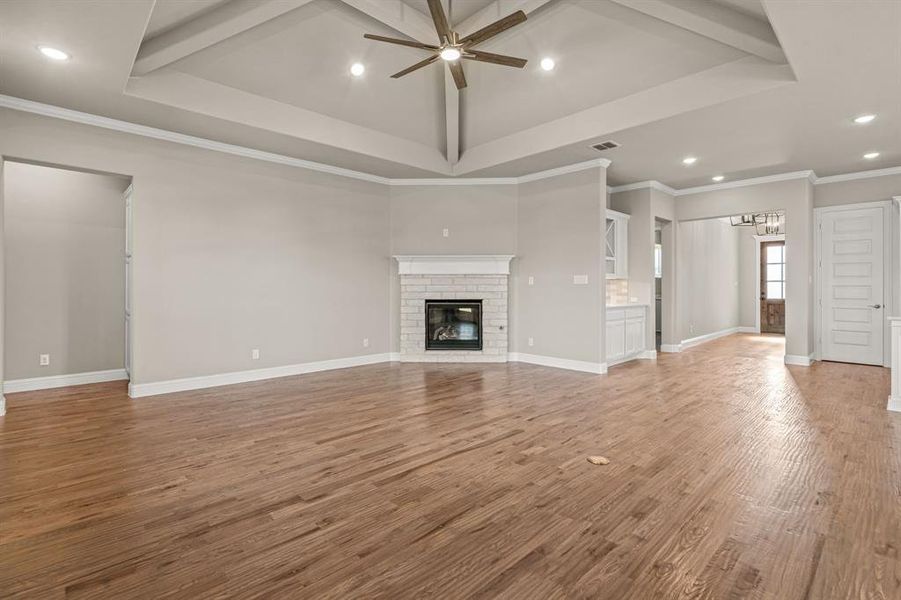 Unfurnished living room featuring recessed lighting, light wood-style floors, a fireplace, beamed ceiling, and ceiling fan Unfurnished living room featuring recessed lighting, light wood-style floors, a fireplace, beamed ceiling, and ceiling fan
