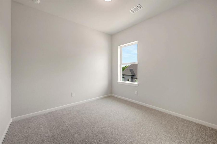 Carpeted interior space featuring light-toned walls, white trim, and a prominent window Carpeted interior space featuring light-toned walls, white trim, and a prominent window