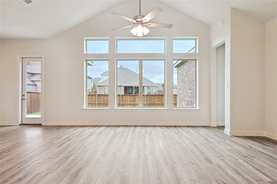 Unfurnished living room featuring ceiling fan, light hardwood / wood-style floors, and high vaulted ceiling