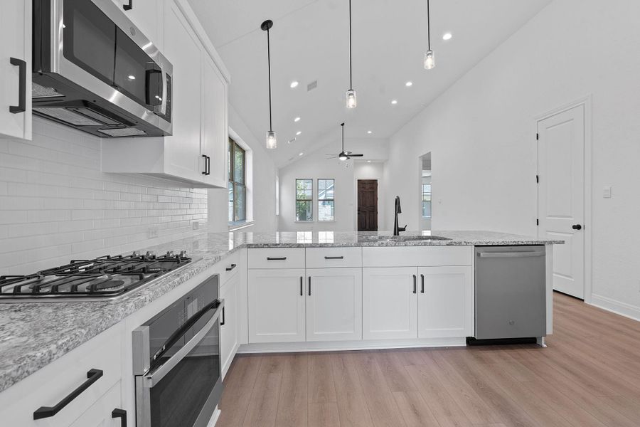 Kitchen featuring stainless steel appliances, white cabinets, light stone counters, recessed lighting, and light wood-style floors