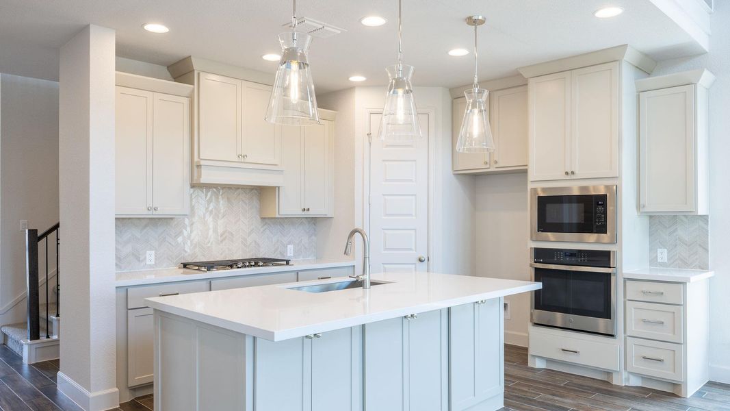 Kitchen featuring decorative backsplash, wood tiled floors, appliances with stainless steel finishes, recessed lighting, and light stone counters Kitchen featuring decorative backsplash, wood tiled floors, appliances with stainless steel finishes, recessed lighting, and light stone counters