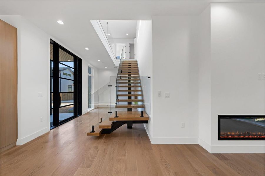 Foyer with wood finished floors, recessed lighting, and a glass covered fireplace