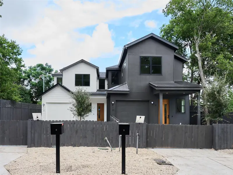 Traditional-style house featuring a metal roof, a fenced front yard, an attached garage, and concrete driveway Traditional-style house featuring a metal roof, a fenced front yard, an attached garage, and concrete driveway