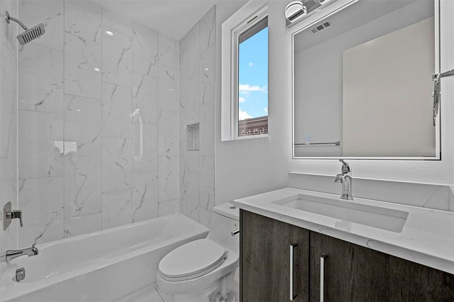 Full bathroom with toilet, vanity, and tiled shower / bath combo