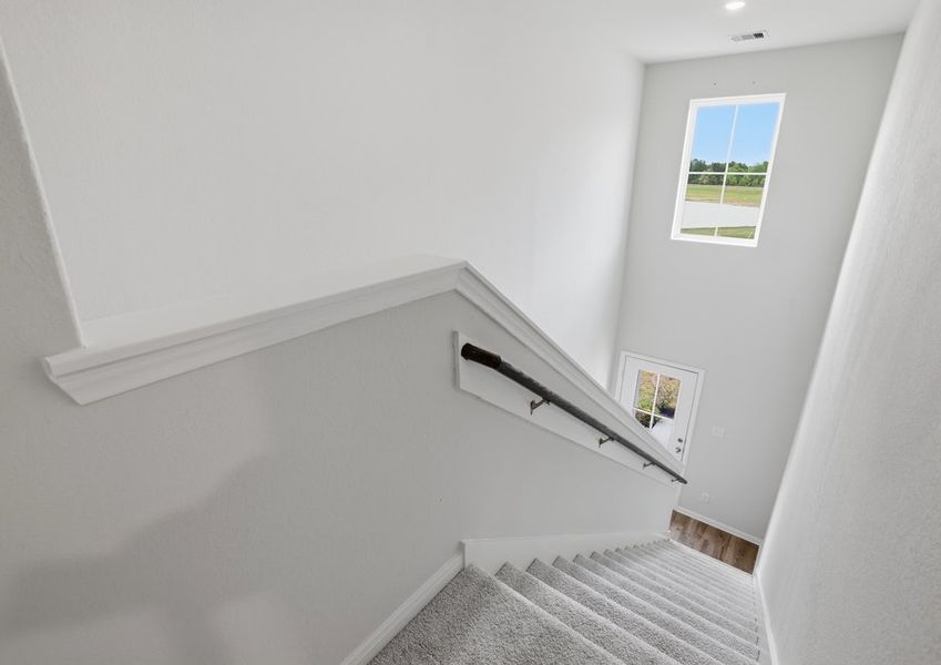 Second-floor landing overlooking the carpeted staircase, with a window providing natural light.