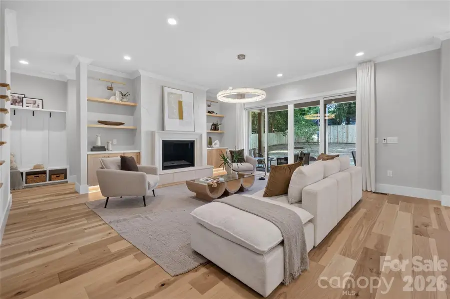 Look at those floors! 10 ft ceilings, signature lighting element, trending Venetian Plaster surround gas fireplace with precast frame, additional dimmable toe kick lighting, shelf lighting & dual glass sliders lead to covered back porch.