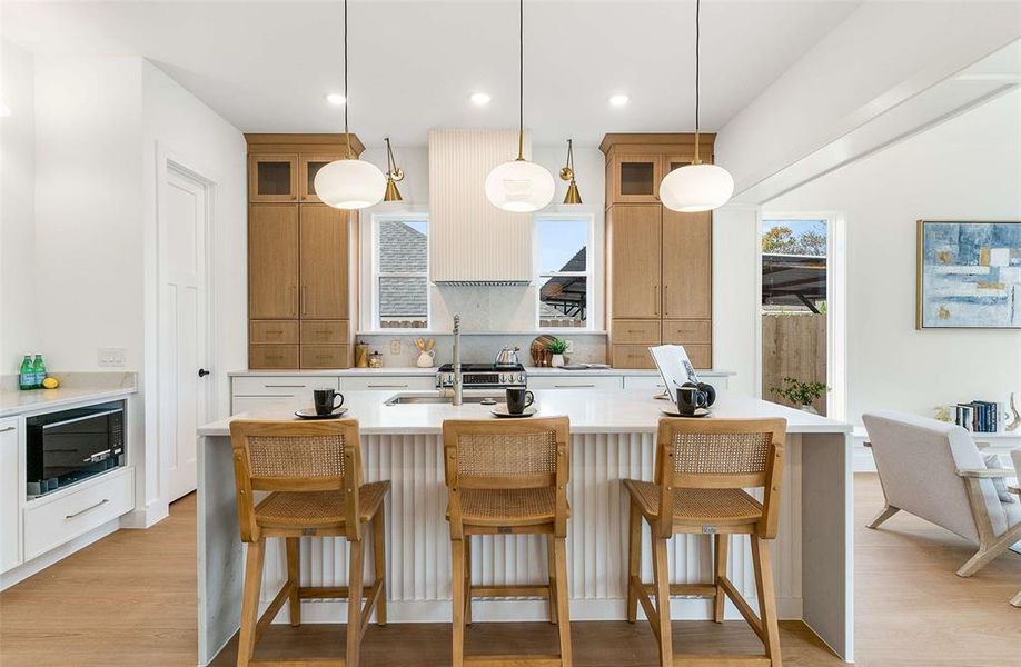 Kitchen with a kitchen bar, light stone counters, healthy amount of natural light, a center island with sink, and recessed lighting