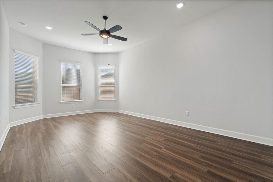 Rich wood plank flooring sets an elegant foundation beneath crisp walls and bright bay windows.
