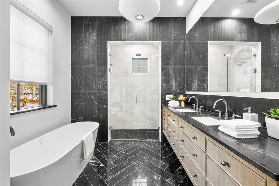 Bathroom featuring a shower stall, tile walls, double vanity, and a soaking tub