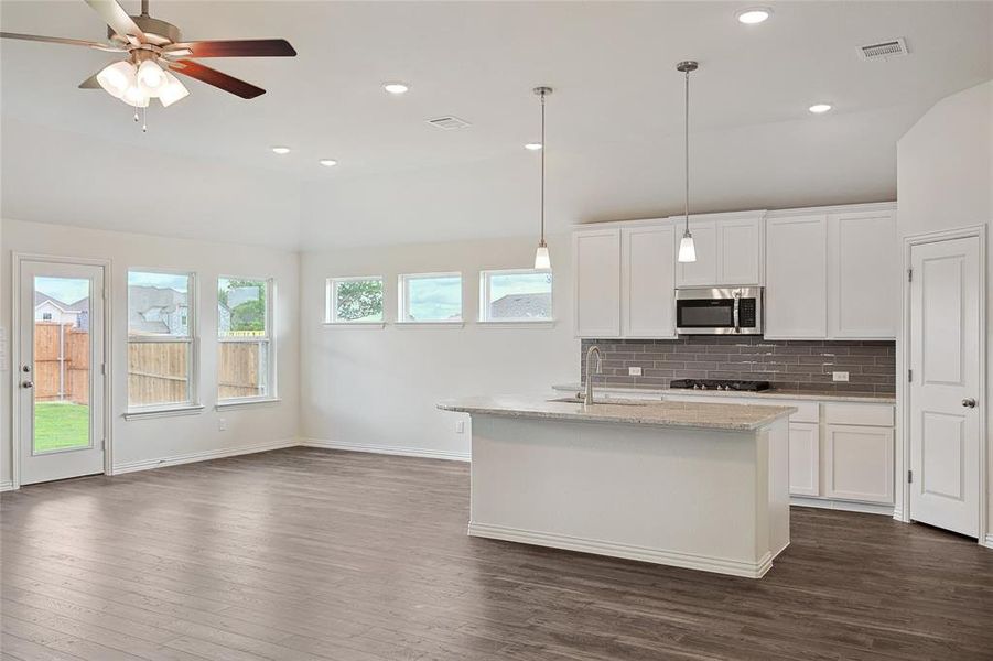 Kitchen featuring backsplash, dark wood-type flooring, sink, and white cabinetry