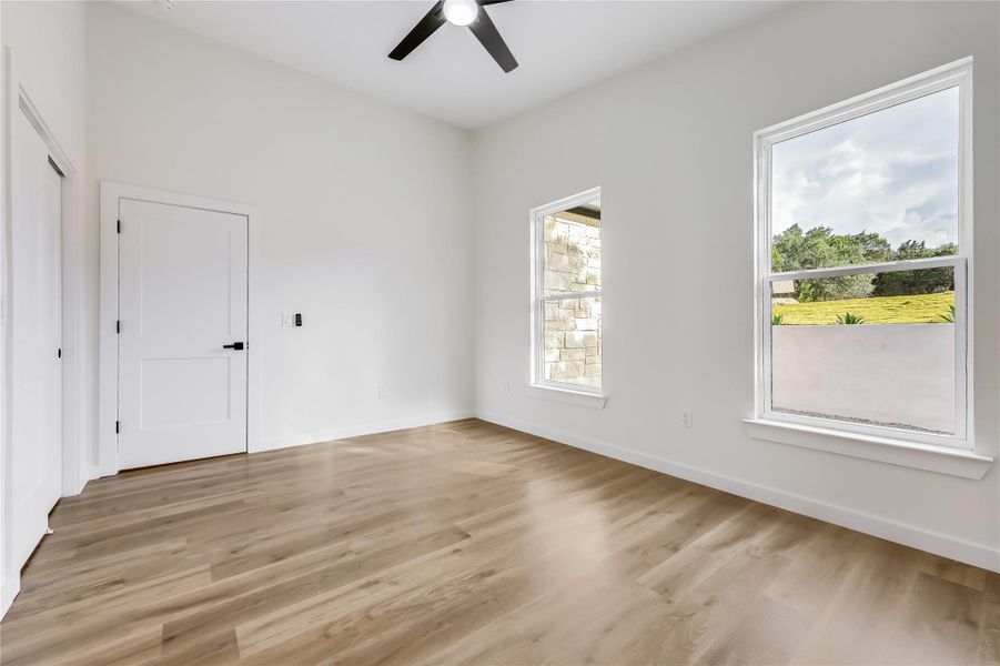 Unfurnished room featuring plenty of natural light, ceiling fan, and light wood-type flooring Unfurnished room featuring plenty of natural light, ceiling fan, and light wood-type flooring