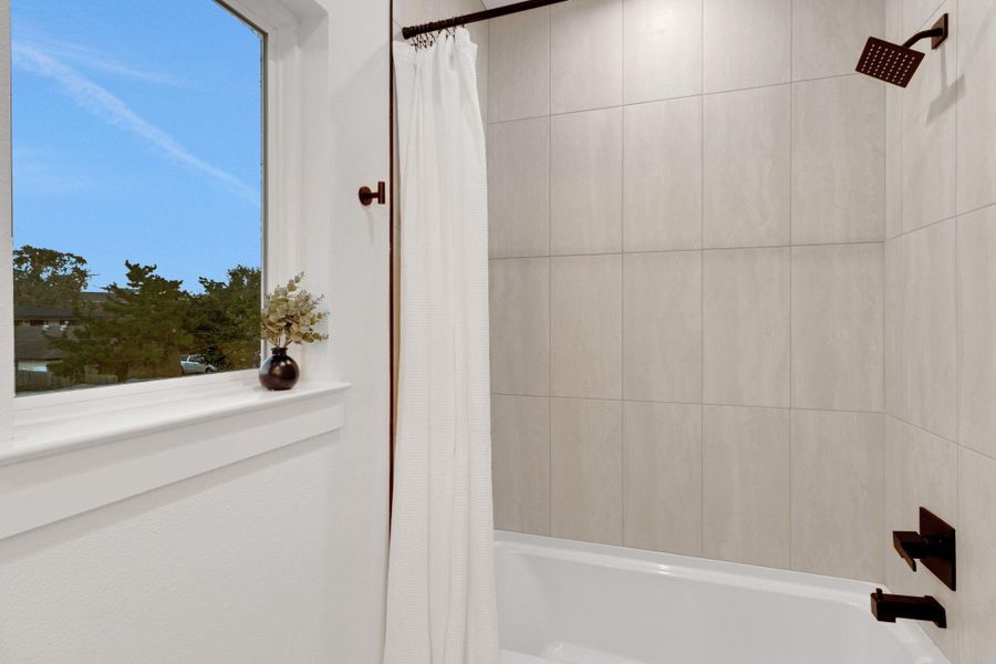 Full bath featuring a deep soaking tub with modern tile surround and a large window that brings in natural light, creating a relaxing retreat. Full bath featuring a deep soaking tub with modern tile surround and a large window that brings in natural light, creating a relaxing retreat.