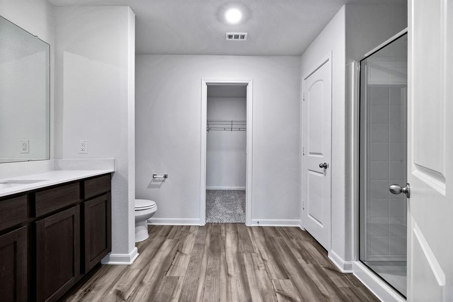 Bathroom with a shower with door, vanity, toilet, and hardwood / wood-style floors