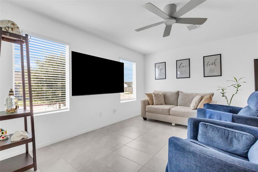 Living room with light tile patterned floors and a ceiling fan