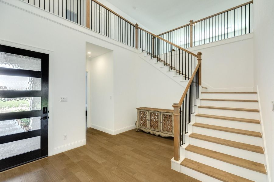 Elegant open floor plan featuring an abundance of natural light, spacious living areas, and a striking custom staircase that serves as the home's centerpiece
