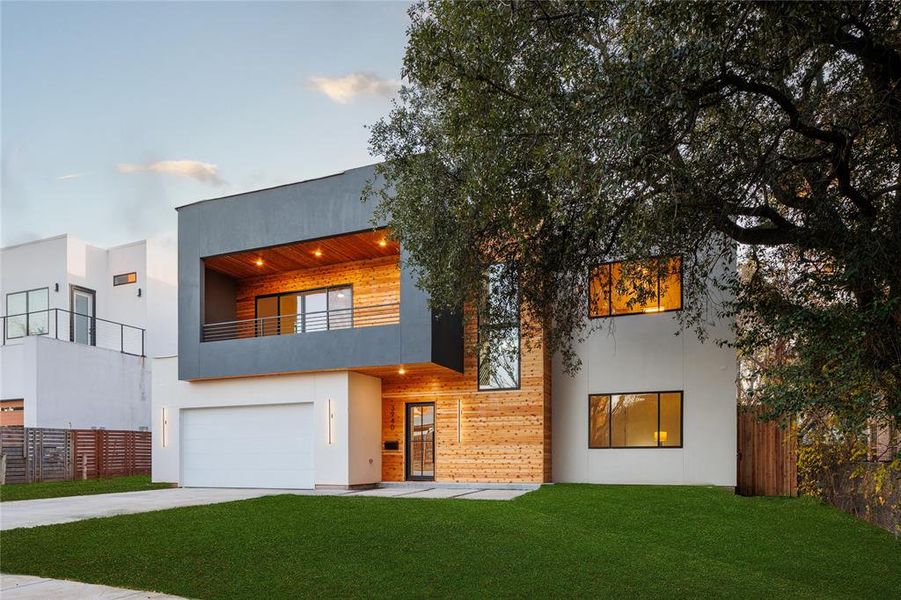 Contemporary home with a balcony, a garage, and a front lawn