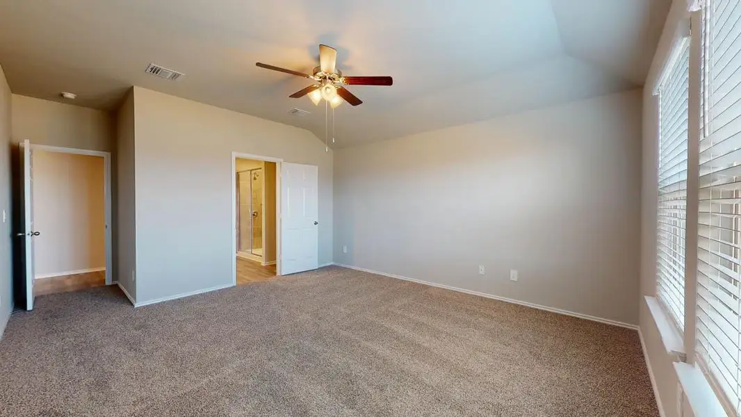 Unfurnished bedroom featuring vaulted ceiling, a ceiling fan, light colored carpet, and connected bathroom