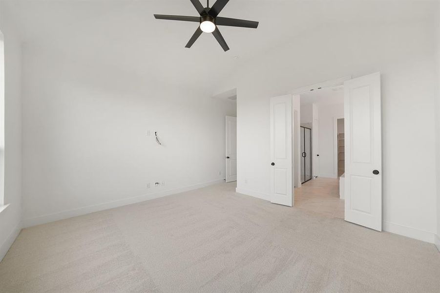 Spare room featuring light colored carpet, vaulted ceiling, and a ceiling fan
