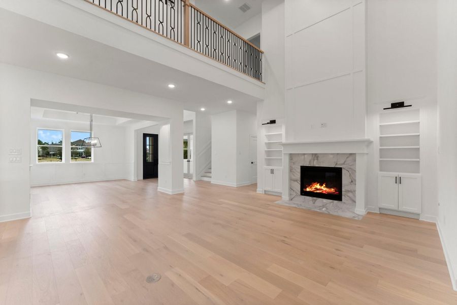 This spacious living area features high ceilings, a modern fireplace with a marble surround, light wood flooring, and built-in shelves. This spacious living area features high ceilings, a modern fireplace with a marble surround, light wood flooring, and built-in shelves.