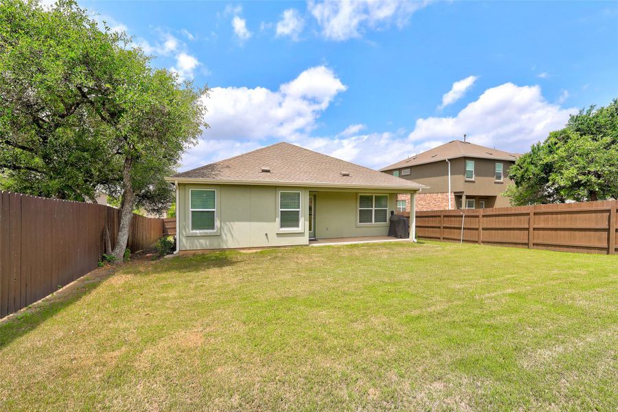 Expansive private backyard featuring a full perimeter privacy fence, mature trees, and a concrete patio