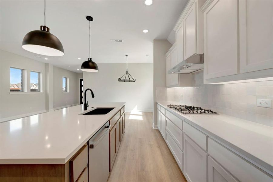 Two tone kitchen with a spacious island, pendant lighting, stainless steel appliances, light wood-style floors, and dual tone cabinetry