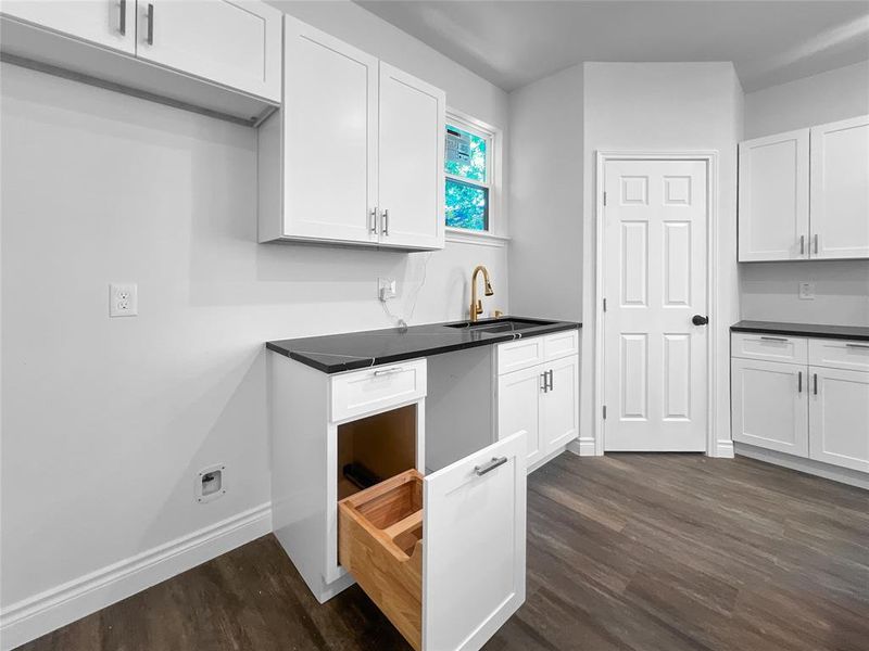 Kitchen featuring dark wood-type flooring, white cabinetry, and sink