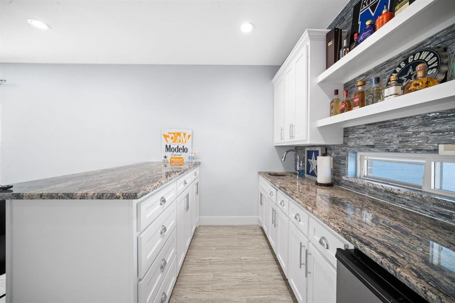 Kitchen featuring a peninsula, dark stone counters, white cabinets, open shelves, and recessed lighting