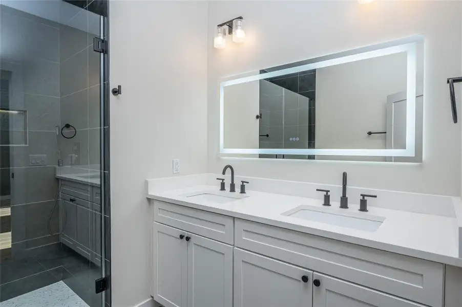 Full bathroom with double vanity and a shower stall