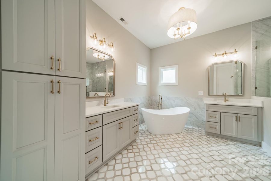 Your stunning Master Suite boasts beautiful custom lighting, cabinetry, tilework, a soaking tub, and a spacious shower.