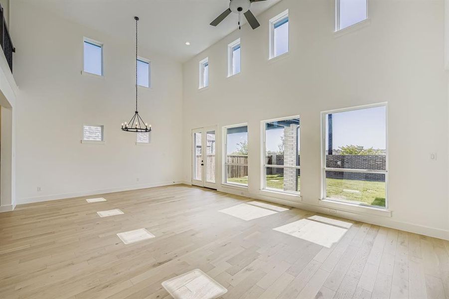 Unfurnished dining area featuring light wood-style flooring, a chandelier, ceiling fan, and plenty of natural light Unfurnished dining area featuring light wood-style flooring, a chandelier, ceiling fan, and plenty of natural light