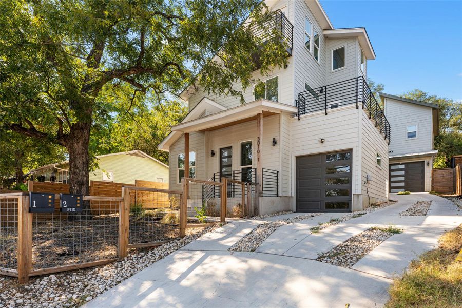 View of front of home featuring a gate, a fenced front yard, concrete driveway, an attached garage, and a balcony