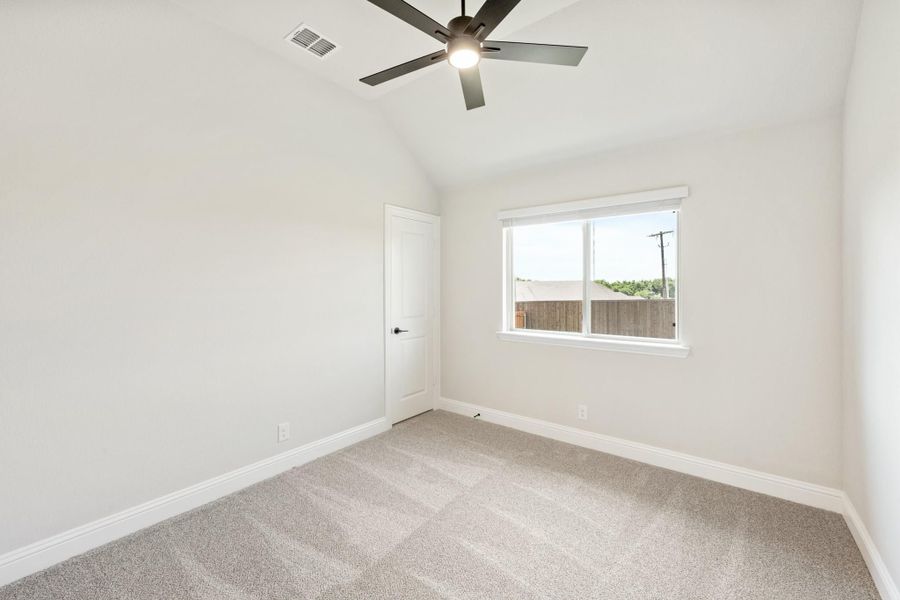 Empty bedroom with vaulted ceiling, ceiling fan, carpet flooring, and a single window Empty bedroom with vaulted ceiling, ceiling fan, carpet flooring, and a single window