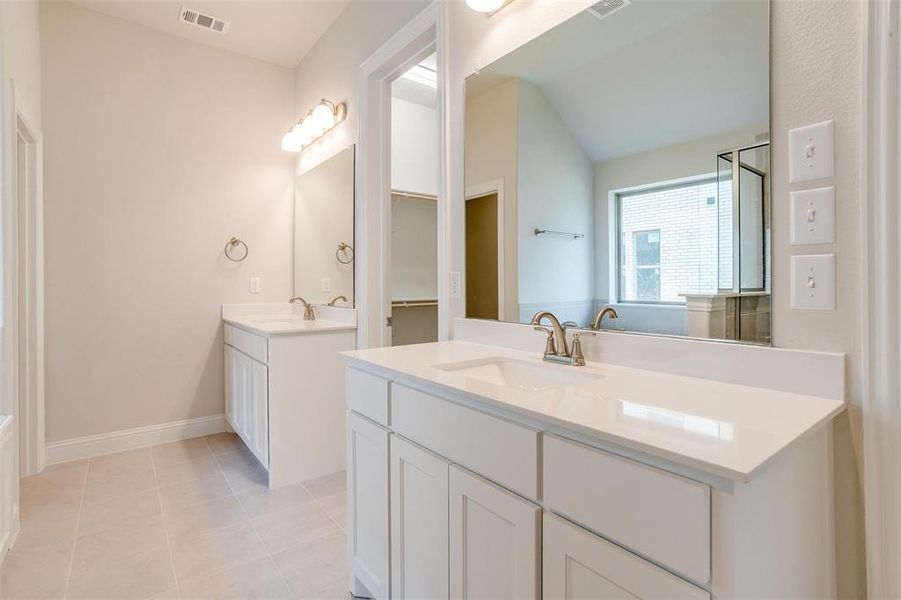 Bathroom with dual vanity, tile patterned floors, and a tub to relax in